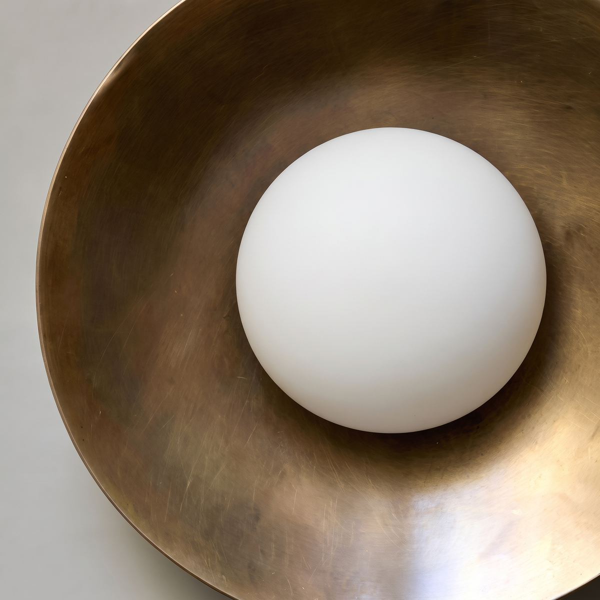 Alabaster orb centered in patinated bronze dish of round wall sconce