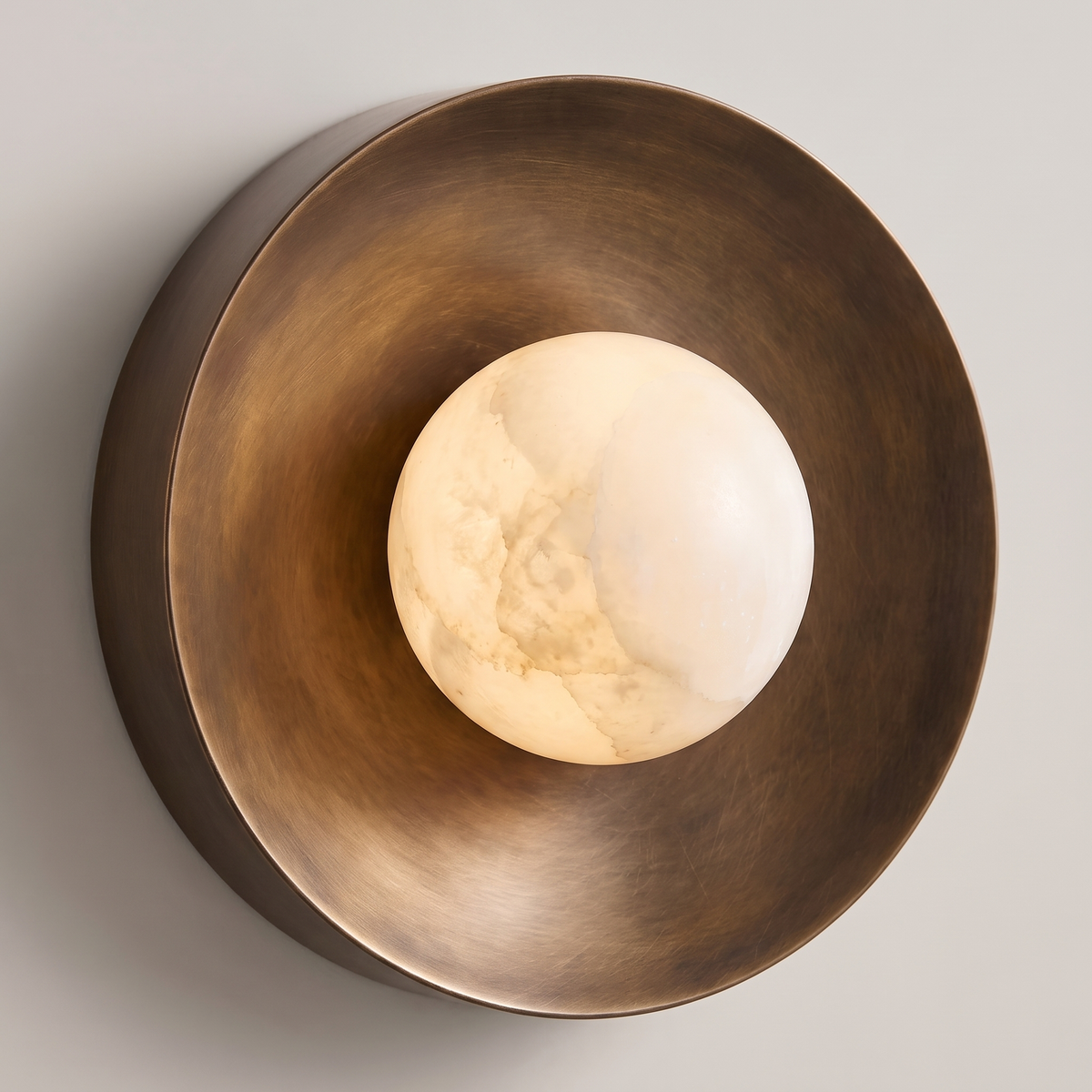 Lit bronze wall sconce with glowing alabaster globe, side angle