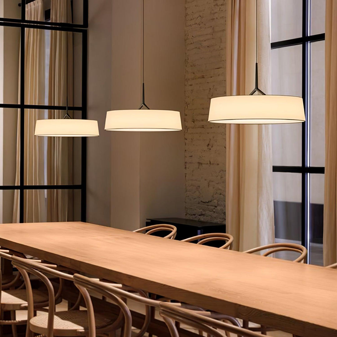 Modern conference room with wooden table and chairs, illuminated by pendant lights.