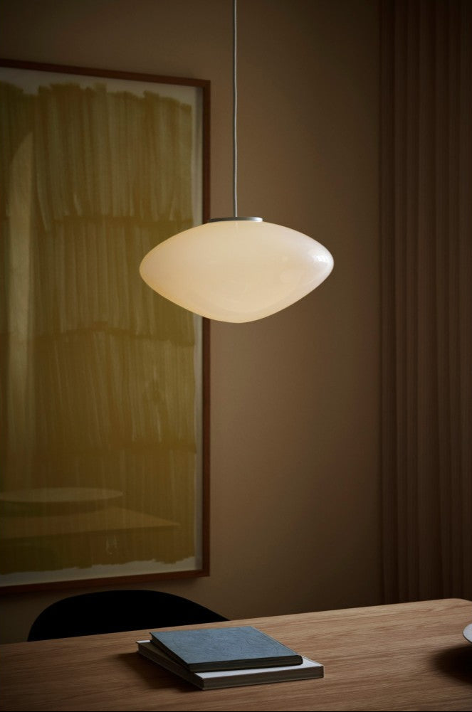 Pendant light fixture hanging above a wooden surface with a blurred background